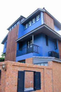 een blauw gebouw met een balkon bovenop een bakstenen gebouw bij P.O.E Posh Homestay in Cha Am