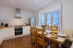 a kitchen with a wooden table with chairs and a dining room at Coastguard House in St Ives
