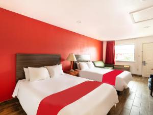 two beds in a hotel room with red walls at OYO Hotel San Antonio near AT&T Center in San Antonio