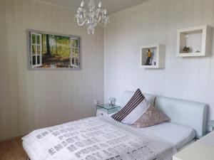 a white bedroom with a bed and a chandelier at Pension Am Mellensee in Saalow