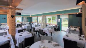 a restaurant with white tables and chairs and windows at Logis Hotel Restaurant Spa Beau Site in Luxeuil-les-Bains