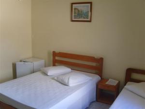 a bedroom with two beds and a picture on the wall at Hotel Modelo in Poços de Caldas