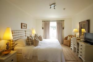 a white bedroom with a bed and a television at Driftwood in Porthscatho