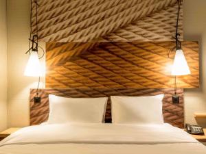 a bedroom with a large bed with two lights above it at ibis Zurich Adliswil in Zürich