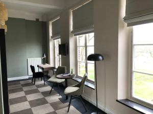 a waiting room with chairs and a table and windows at De Pastorie Bed & Breakfast in Roermond