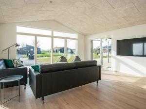 a living room with a black couch and a tv at 12 person holiday home in Haderslev in Haderslev