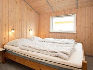 a bed in a room with wooden walls and a window at 8 person holiday home in Stege in Stege