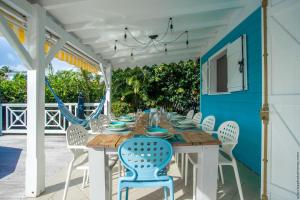 a wooden table and chairs on a porch with a blue wall at CAZA TURQUOIZ in Rivière-Salée
