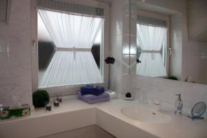 un bagno bianco con lavandino e specchio di Gästehaus Sonja a Durach Altre 12 foto