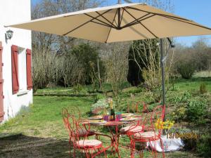 a table and chairs under an umbrella in a yard at Gîte l Idéal in Montsauche