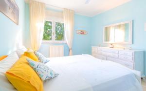 a blue bedroom with a white bed and a window at Villa Christelle Luxury Pescoluse by HDSalento in Marina di Pescoluse