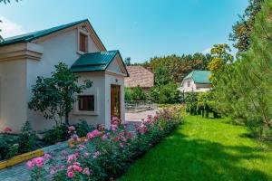 a garden with pink flowers in front of a house at Gоlden Dragon Villa Hotel in Bishkek