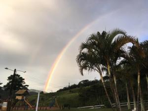 a rainbow in the sky over a playground with palm trees at Pousada Chapadão in Ipiabas