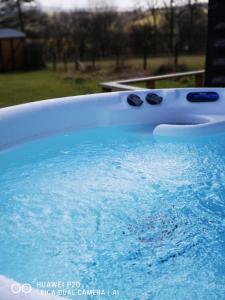 uma banheira cheia de água azul com dois copos pretos em pen-rhos luxury glamping "The Hare Hut" em Llandrindod Wells