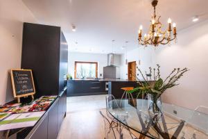 a dining room and kitchen with a glass table and a chandelier at Gîte 7 personnes- Le Refuge du Saule in Burdinne +14 photos