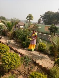 Eine Frau in einem bunten Kleid steht im Garten in der Unterkunft Asian Grand Villa in Bolpur