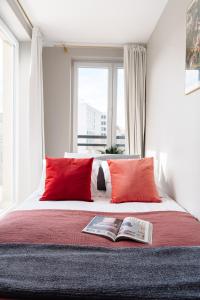 a bed with two red pillows and a book on it at Mellow Apartment by Loft Affair in Krakow