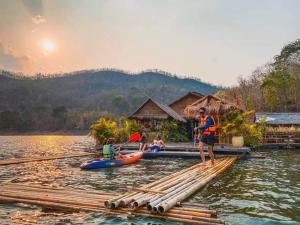 Ein Mann steht auf einem Floß im Wasser in der Unterkunft Sweet Home Floating House in Ban Lum Le