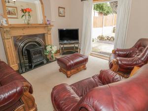 a living room with leather furniture and a fireplace at Jasmine Cottage in Rhyl