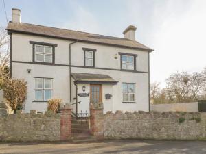 a white house with a stone fence in front of it at Jasmine Cottage in Rhyl
