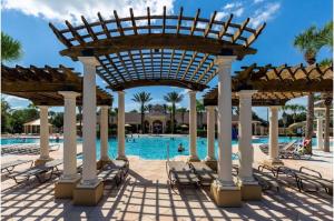 a pool at a resort with chairs and a pavilion at Three-Bedroom Townhome Kissimmee in Orlando