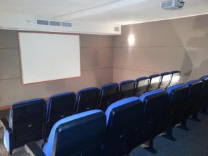 una clase con sillas azules y una pantalla blanca en My Aparts SCL, en Santiago