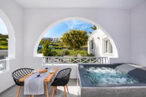 a hot tub on a balcony with a table and chairs at Abasa Suites in Fira