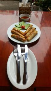zwei Teller Essen auf einem Tisch mit Gabel und Messer in der Unterkunft Quang Quang Garden Bonsai Homestay in Ninh Bình