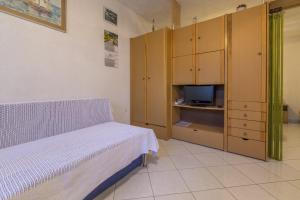 um quarto com uma cama, uma televisão e armários em JOVANOVIC em Selce