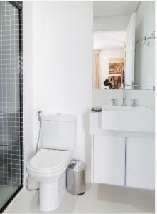 Baño blanco con aseo y lavamanos en Geo Berrini Apartment, en São Paulo