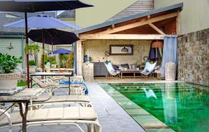 a swimming pool with chairs and umbrellas next to a house at Appartements & Spa de la Marine Loire in Montsoreau