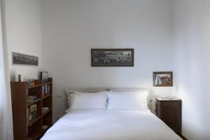 a bedroom with a white bed and a book shelf at Cozy Family Apartment in Castelletto in Genova