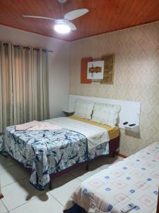 a bedroom with two beds and a ceiling fan at Pousada Angela in Urubici