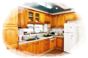 a kitchen with wooden cabinets and a white refrigerator at Sun Flower Minbak in Seogwipo
