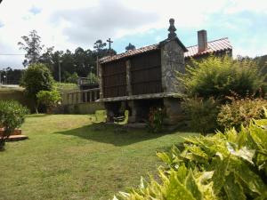 a house in a garden with two chairs at Casa Camino Santiago-Fisterra in Amés