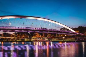 a bridge over the water at night with purple lights at Modern Studio Węgierska Cracow by Renters in Krakow