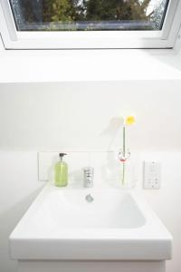 a white bathroom sink with a window above it at The Barn in Chichester