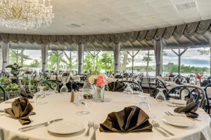 un comedor con mesas blancas y sillas negras en Bonnie Castle Resort & Marina en Alexandria Bay