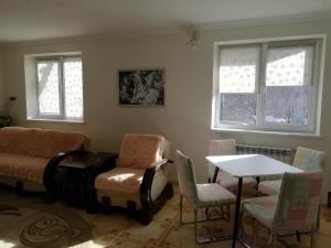 a living room with chairs and a table and windows at Трускавець Апартаменти. in Truskavets