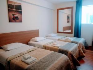 Habitación con 3 camas y espejo. en Hotel Paris Lima, en Lima