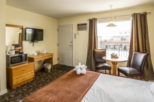 Habitación de hotel con cama y TV en Oasis Inn, en Kelowna