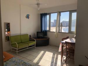 ein Wohnzimmer mit einer grünen Couch und einem Tisch in der Unterkunft APARTAMENTO FRENTE A PRAIA SAO VICENTE in São Vicente