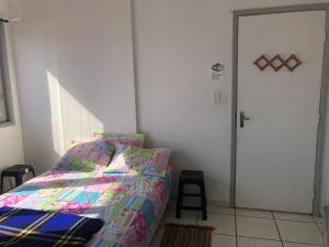 1 dormitorio con cama, puerta y taburete en APARTAMENTO FRENTE A PRAIA SAO VICENTE en São Vicente