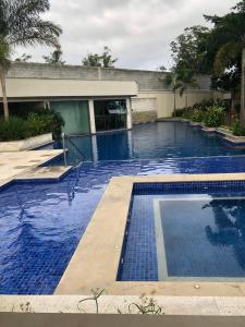 einem Pool mit blauem Wasser vor einem Gebäude in der Unterkunft Flat 507 próximo ao Projac Jacarepaguá in Rio de Janeiro