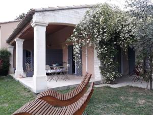 a patio with two wooden benches in a yard at Parfums de Provence "Le Lavandin" Piscine chauffée & Spa in Vaison-la-Romaine