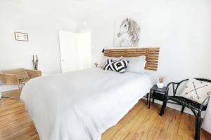 una camera da letto con un grande letto bianco e una sedia di The Explorer's Hearth Lower-Greenville Ave Area a Dallas