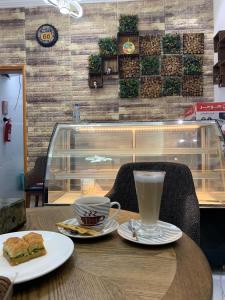 AL JOOD HOTEL APARTMENT في Ḩilf: طاولة مع فنجان قهوة وسندويش