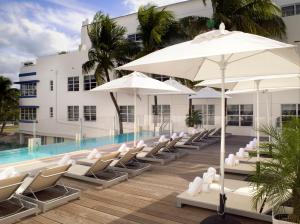 a pool with chairs and umbrellas next to a building at Hotel Breakwater South Beach in Miami Beach