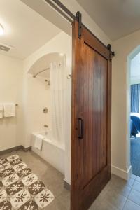 a bathroom with a wooden door and a tub at La Playa Inn Santa Barbara in Santa Barbara