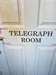 een bord op een witte deur dat de telefoonkamer leest bij The Old Post Office Boutique Guesthouse in Hythe